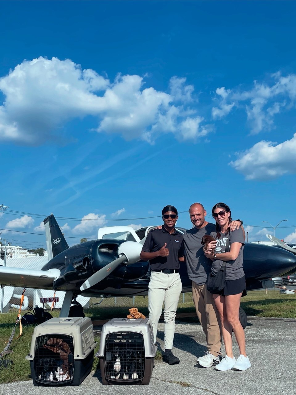 Animal rescue handoff on the tarmac — black Piper N1519T with pet crates and volunteers